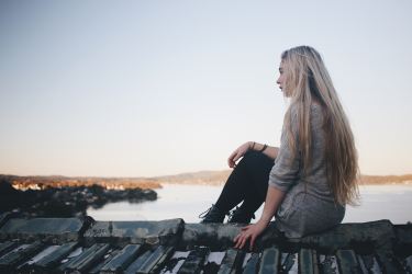 A single girl sitting by the water.