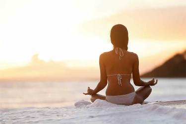 a woman meditating on a beach