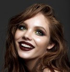 a happy woman wearing red lipstick and green eye shadow