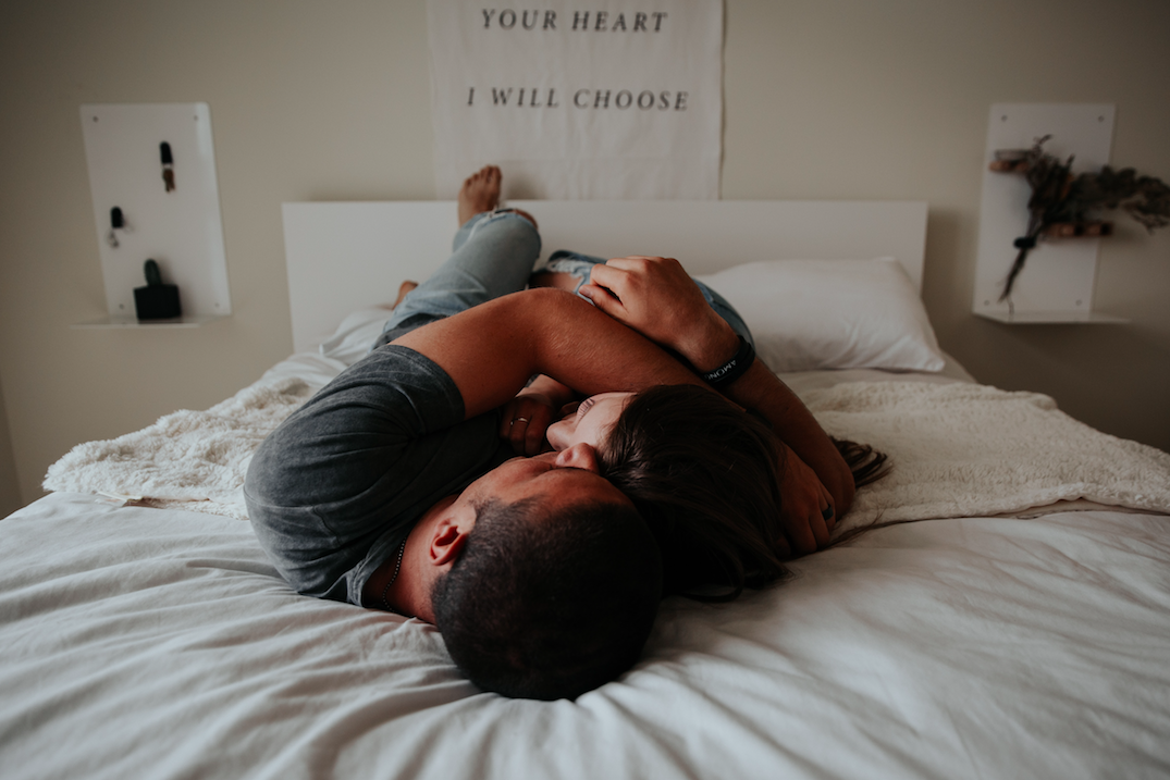 Couple cuddling on bed. Photo by Becca Tapert on Unsplash