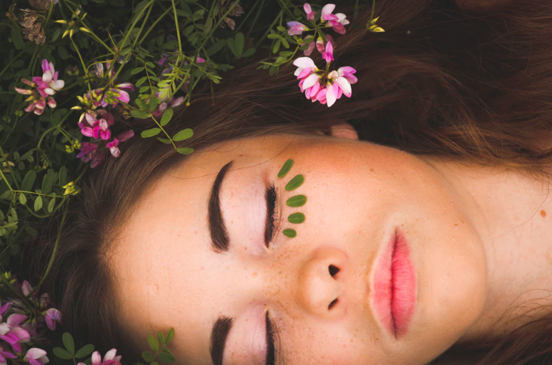 Girl lying on ground with flowers. image by Sarah Coneau from unsplash.com