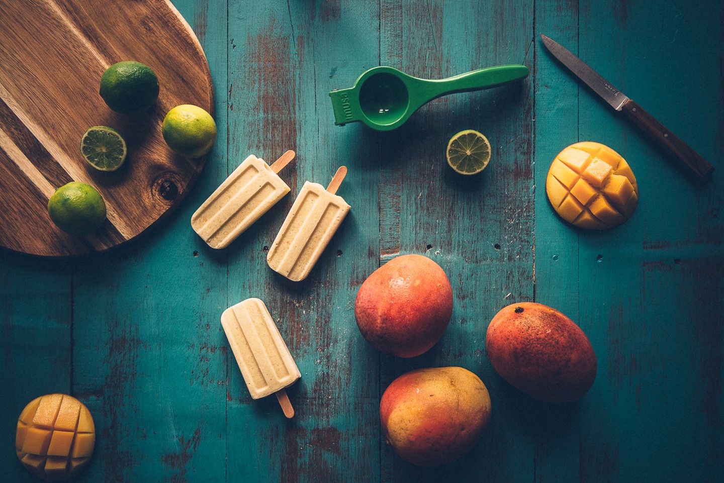 Popsicle flatlay surrounded by mangoes and limes.