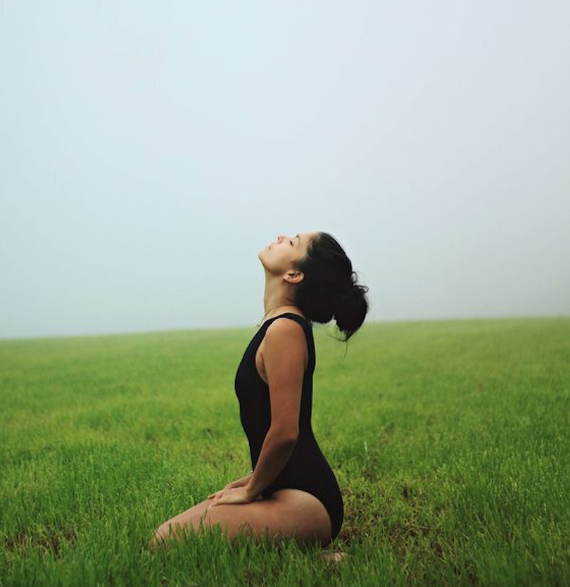 woman in black bodysuit kneeling on a green. field