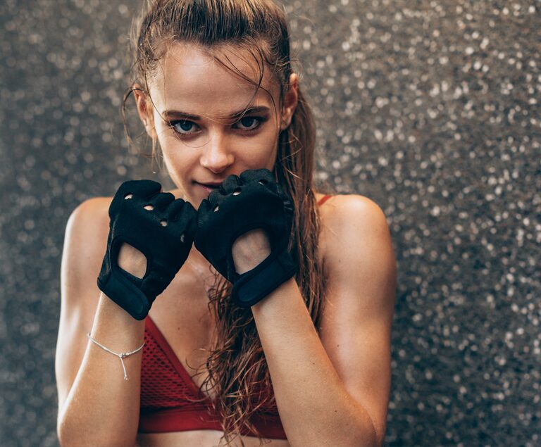 Brunette with long ponytail in boxing gloves and red crop top.