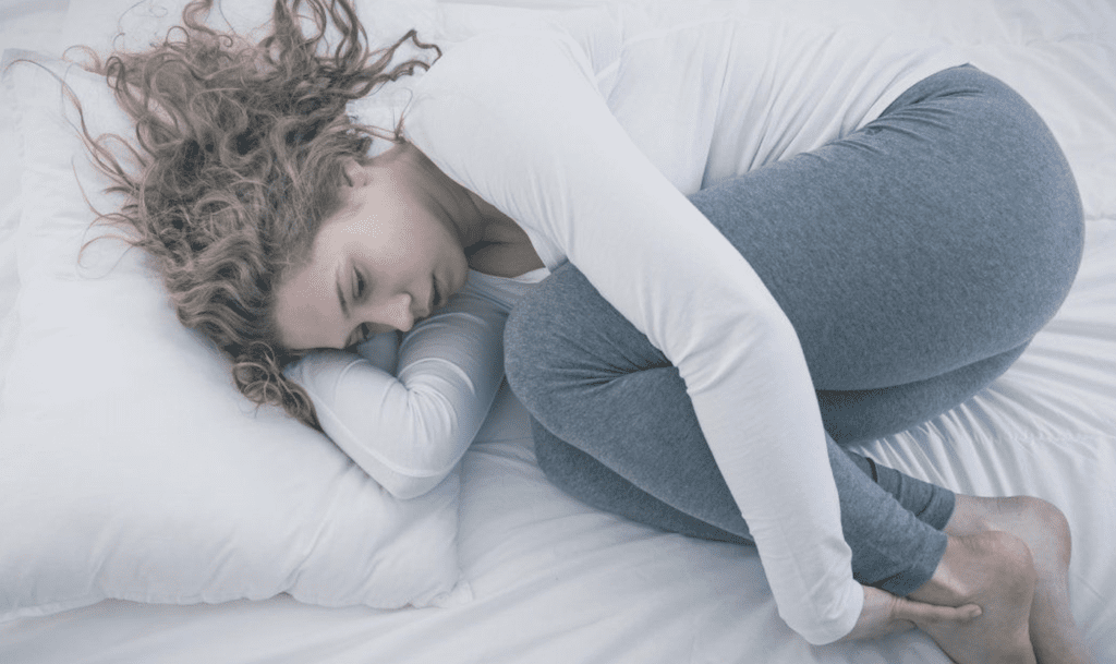 Woman curled up lying on bed
