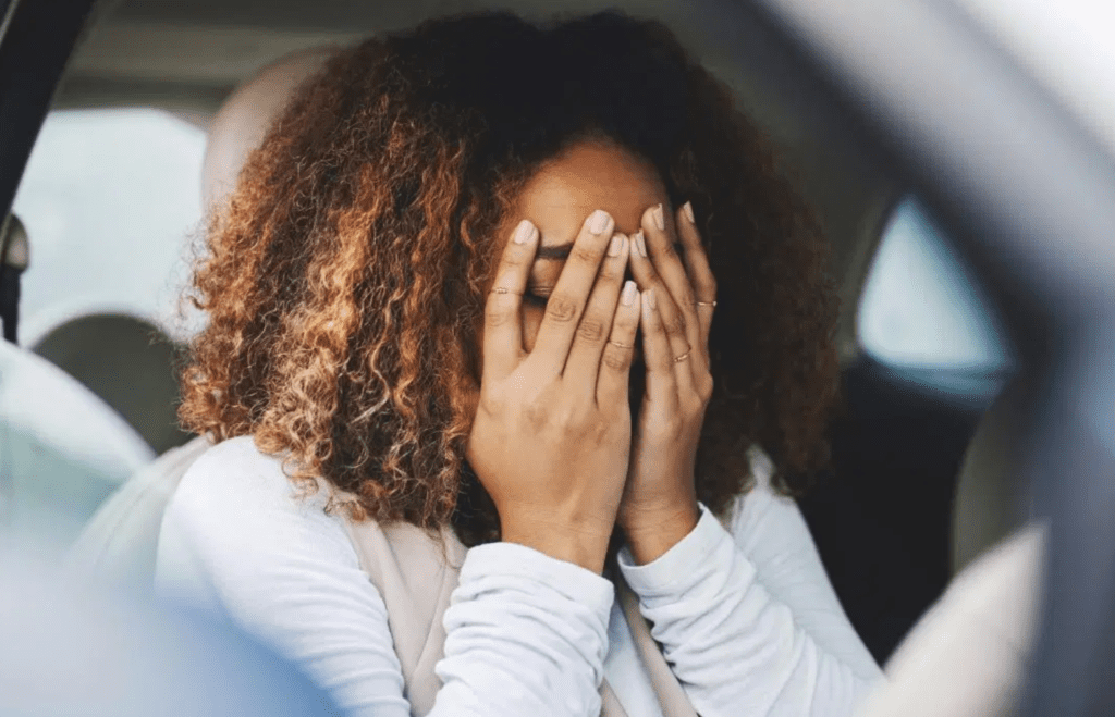 Woman with curly brunette hair burying face in her hands