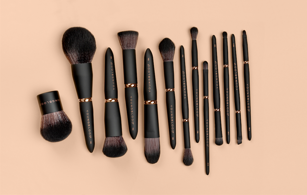 Makeup brushes lined in a row against nude backdrop.