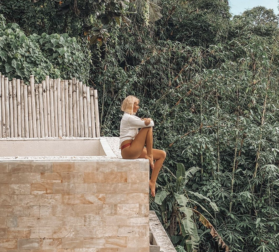 Girl sitting on edge of building in jungle