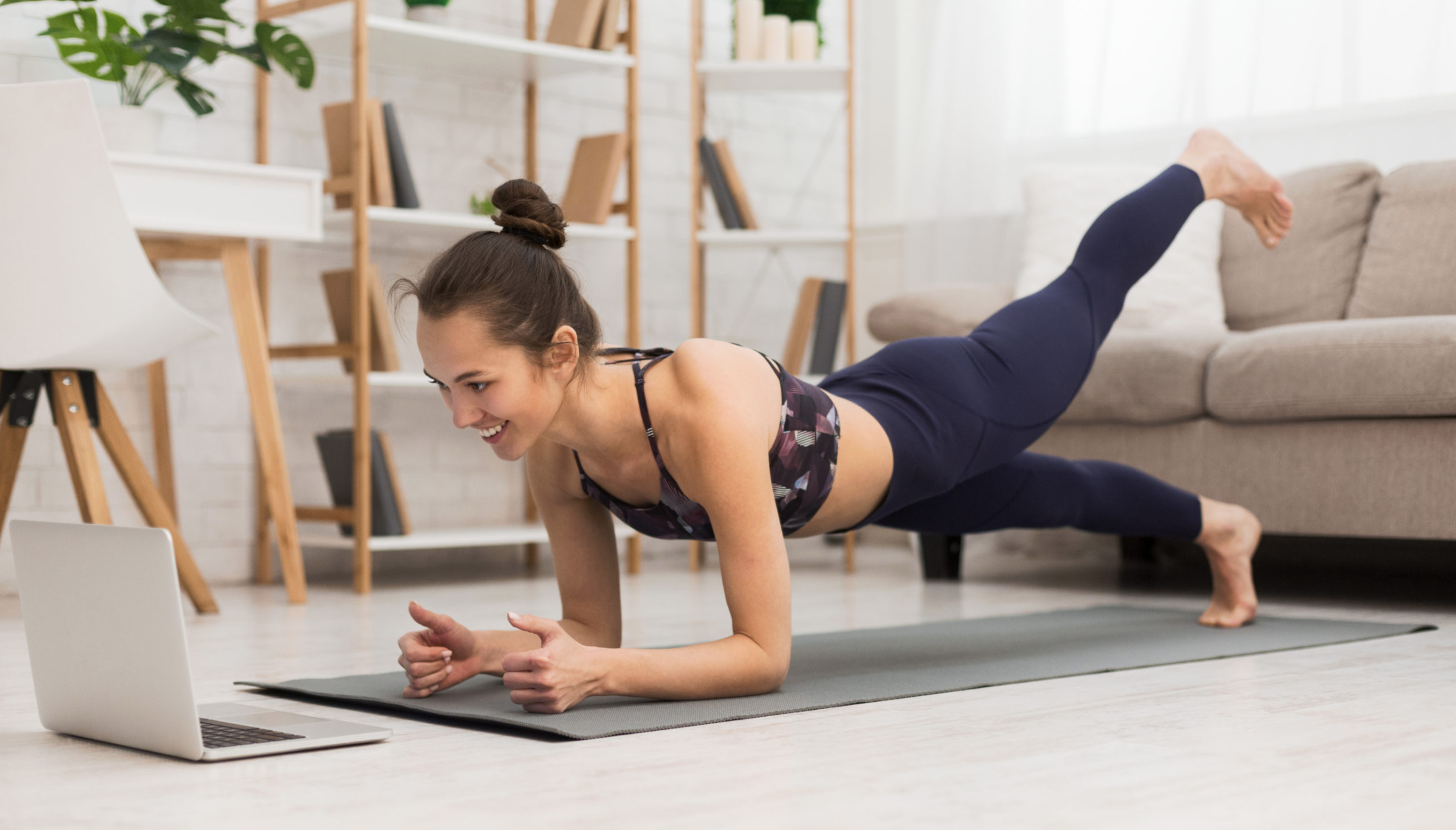 woman on yoga mat in front of laptop