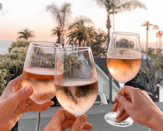 Cheers-ing glasses of rose over a sunset