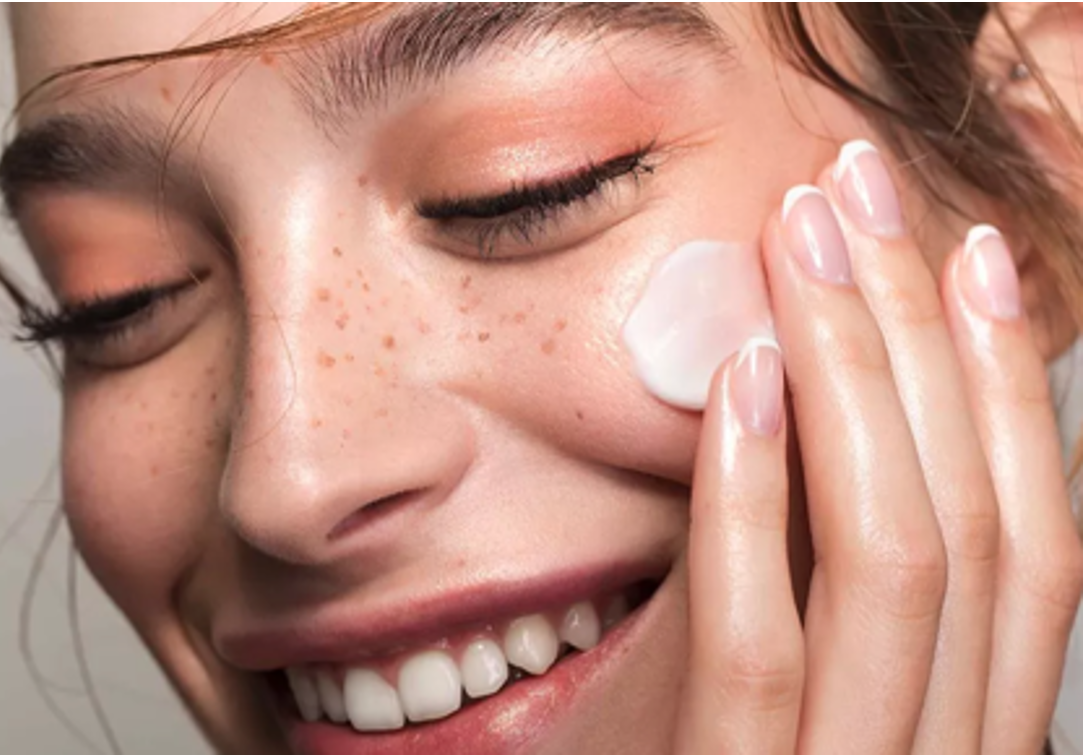 Woman with freckles applying face cream