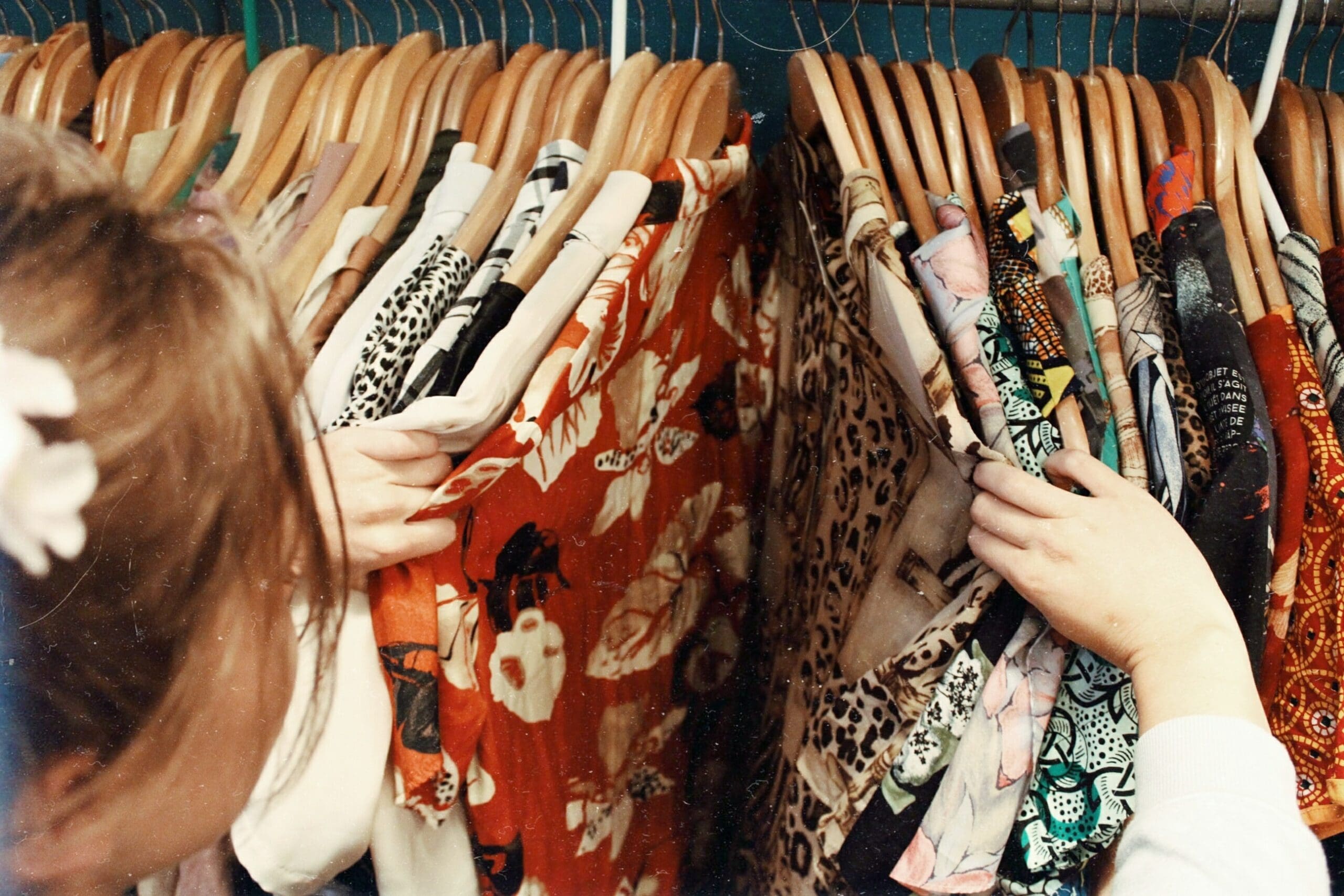 Image of a woman looking through a rack of clothes.