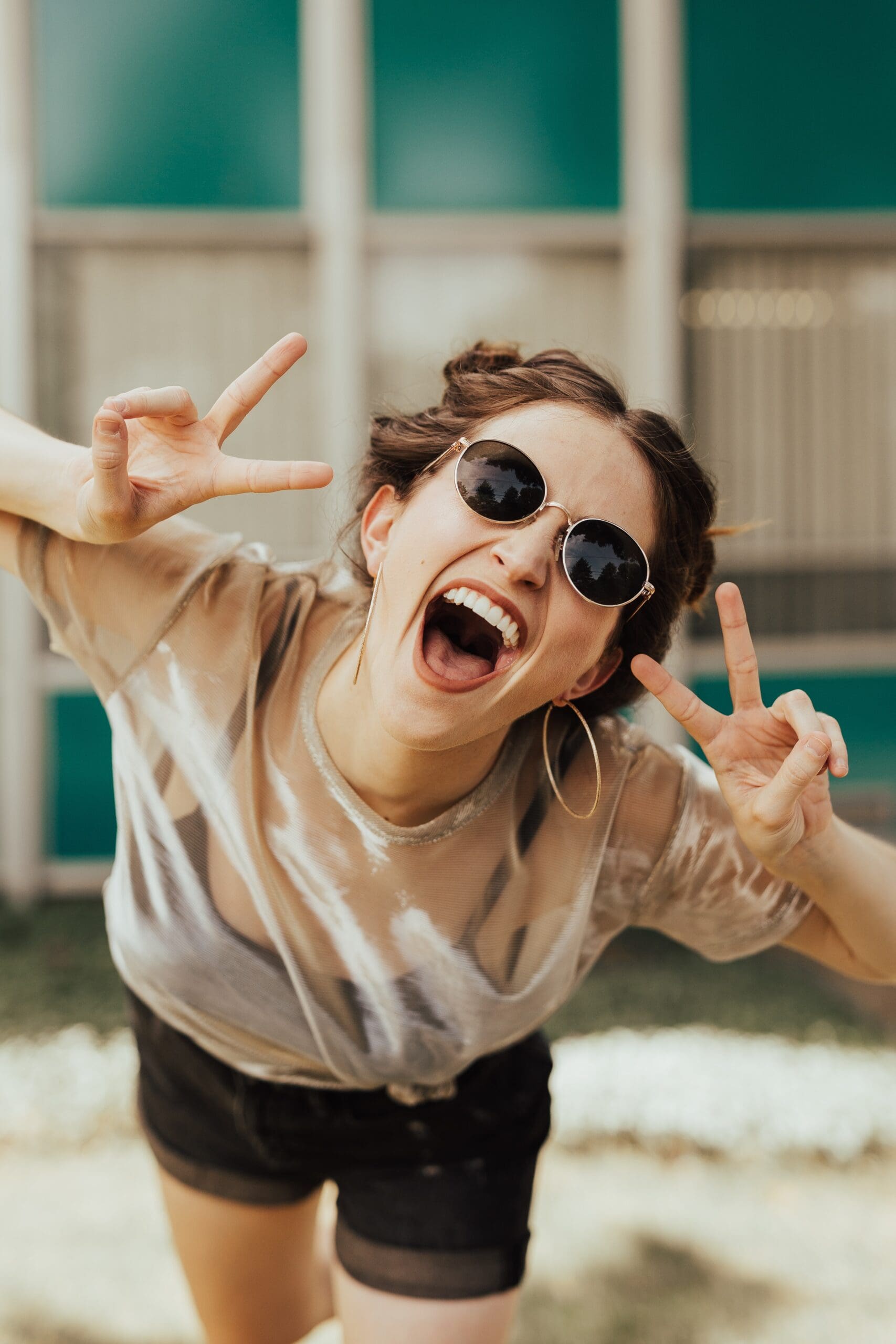 young woman with sunglasses laughing at camera