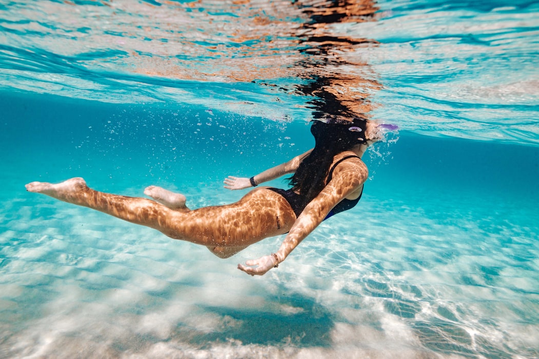 brunette woman in black swimsuit under water