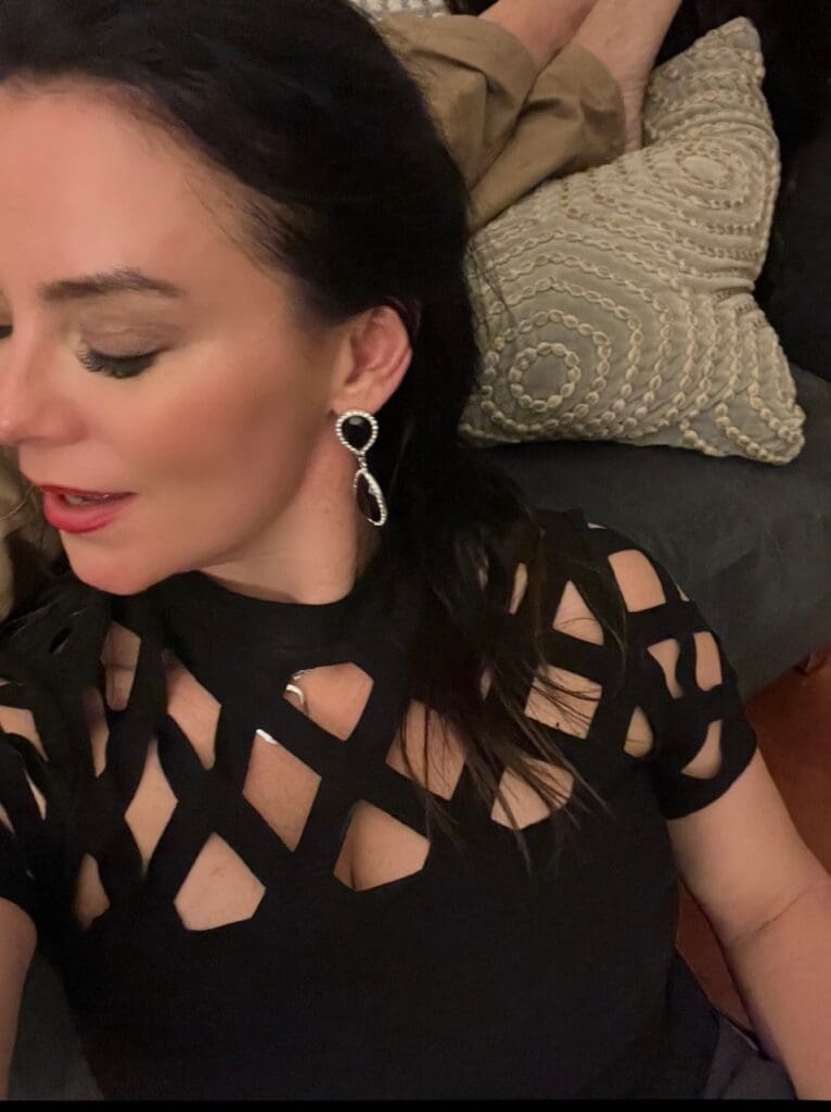 brunette woman with black top and ear-ring and eyes closed