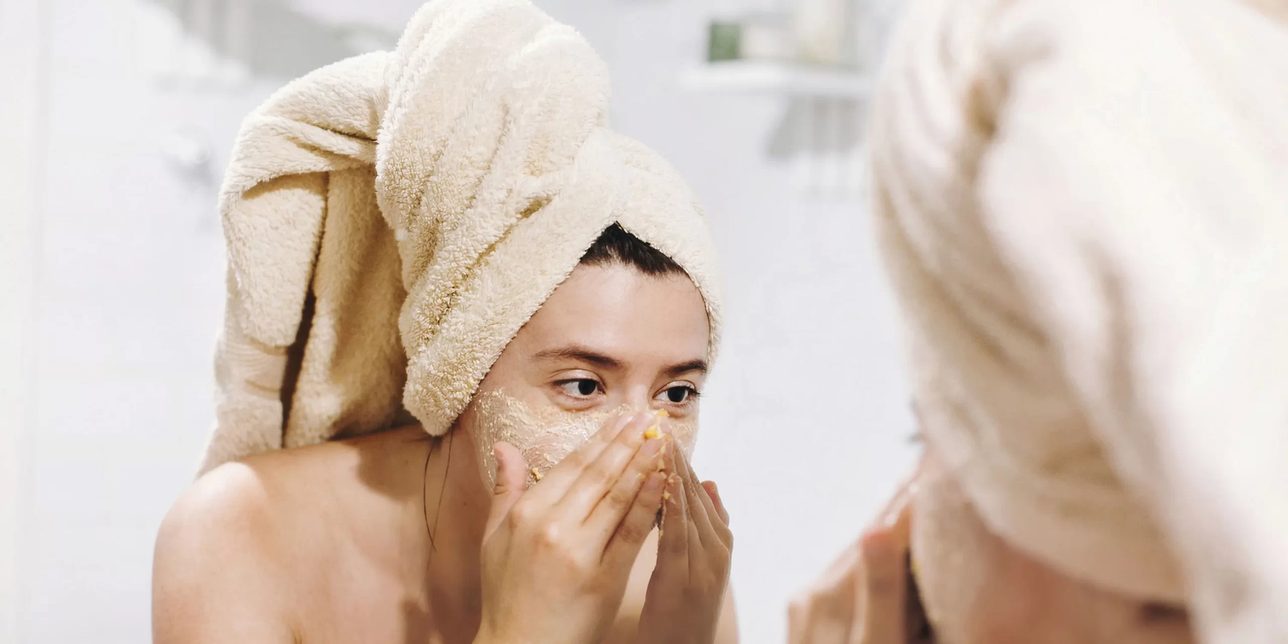 Girl using face scrub in mirror