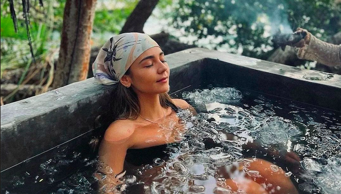 Woman sitting in an ice bath at home, recovering from physical activity and gaining the benefits